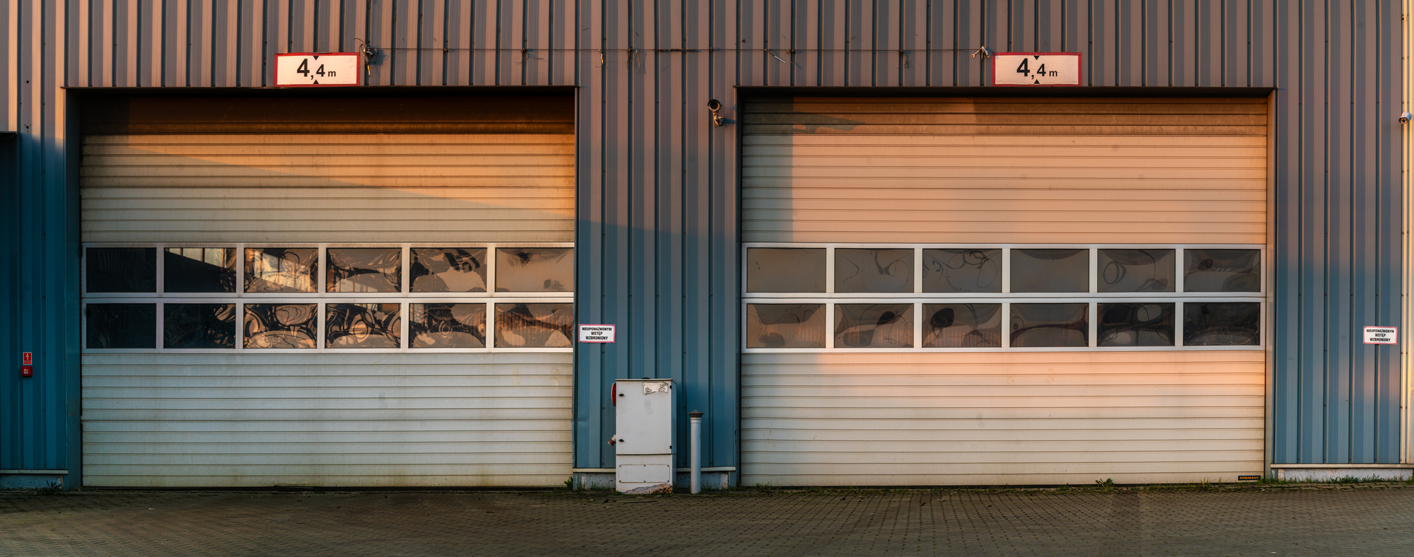 two weathered garage doors side by side for car repair shop with windows see through doors, roll up garage door, overhead garage door.